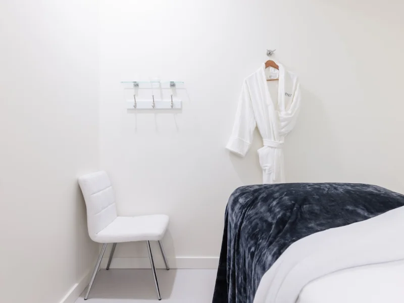 Private spa treatment room with massage bed and robe