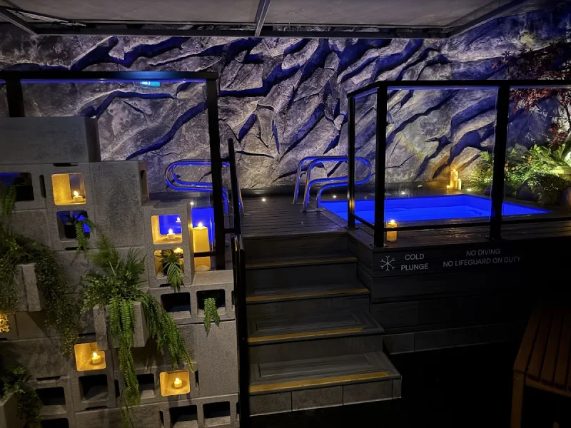 Blue-lit cold plunge pool and spa deck inside AetherHaus