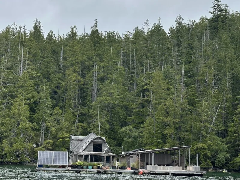 Rustic bathhouse building on water surrounded by dense Pacific Northwest forest