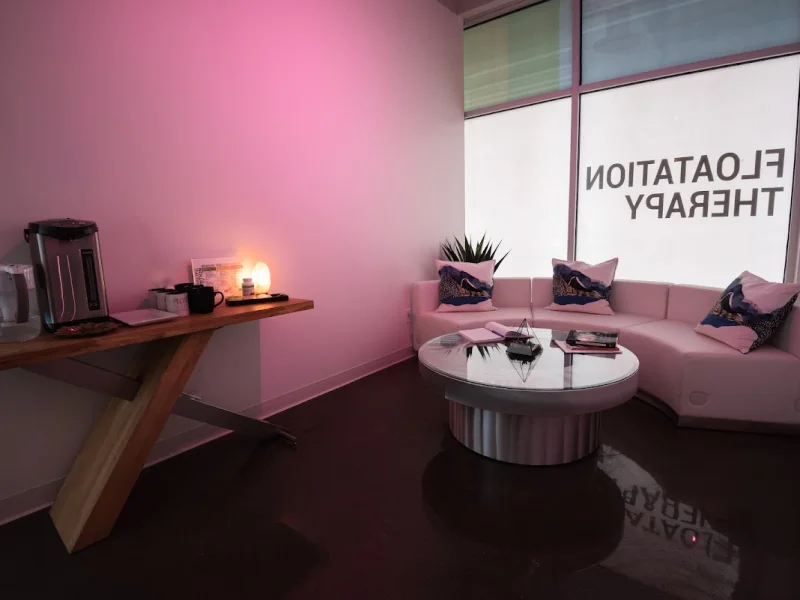 Serene floatation therapy lounge with pink seating, ambient lighting, and relaxation setup