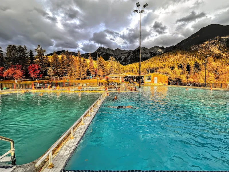 Bright turquoise mineral pools framed by autumn mountains and clouds