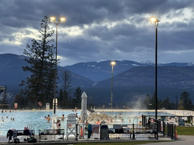 Steam rising over outdoor thermal pools with mountain skyline at dusk