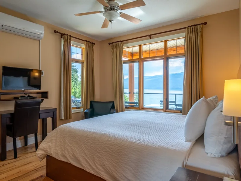 Waterfront bedroom suite with king bed and lake views through glass walls