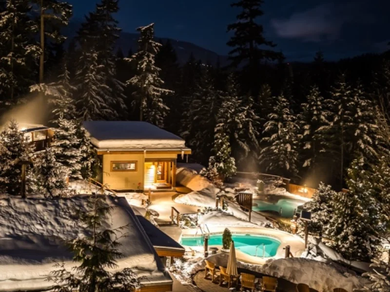 Snowy nighttime outdoor spa pools surrounded by forest at Scandinave Spa Whistler