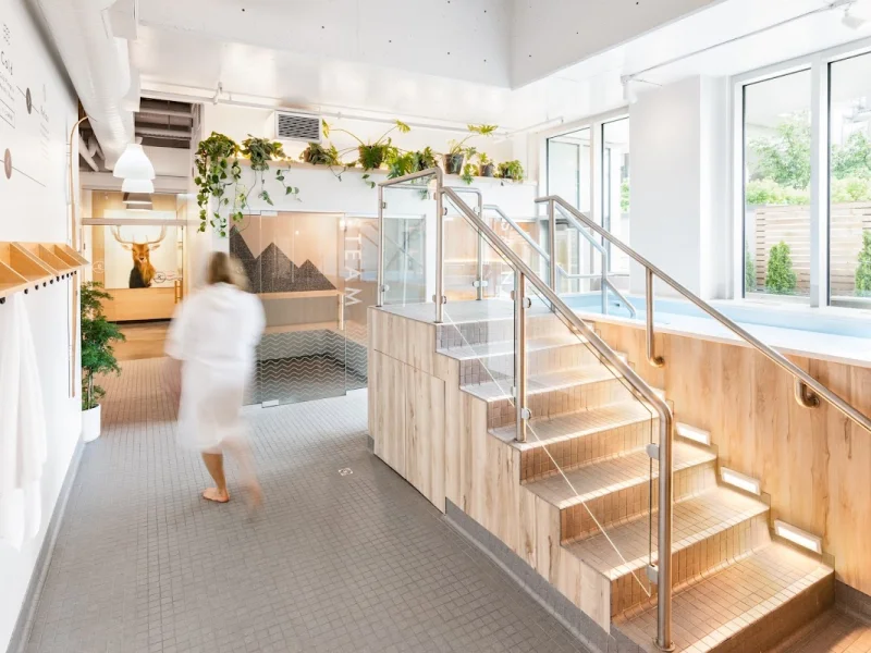 Wide view of bright spa lobby with plants, stairs, and pool entrance