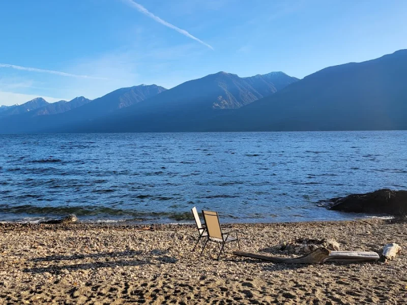 Pebble beach lounge with chairs beside a mountain lake
