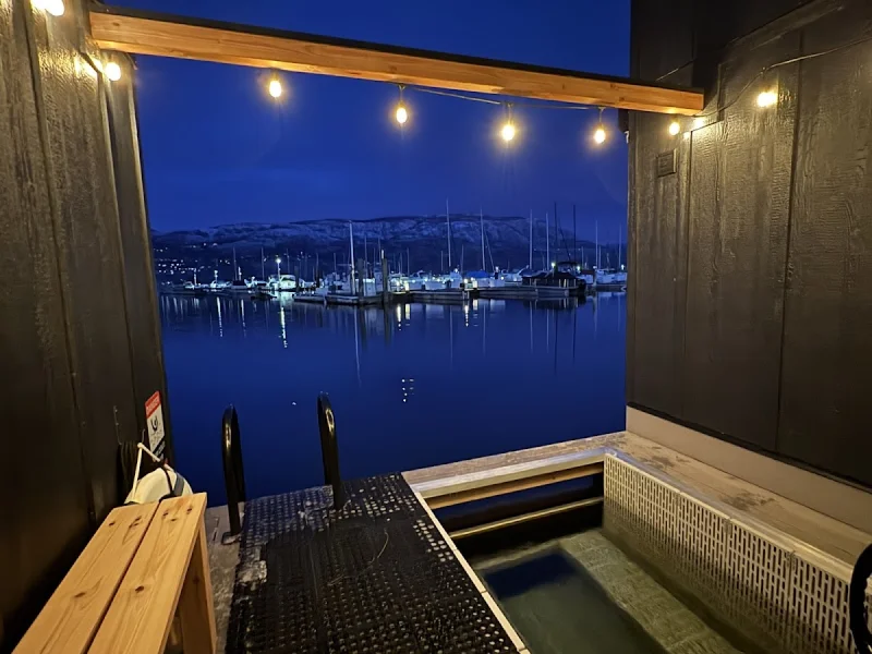 Nighttime floating sauna deck with cold plunge and marina mountain views