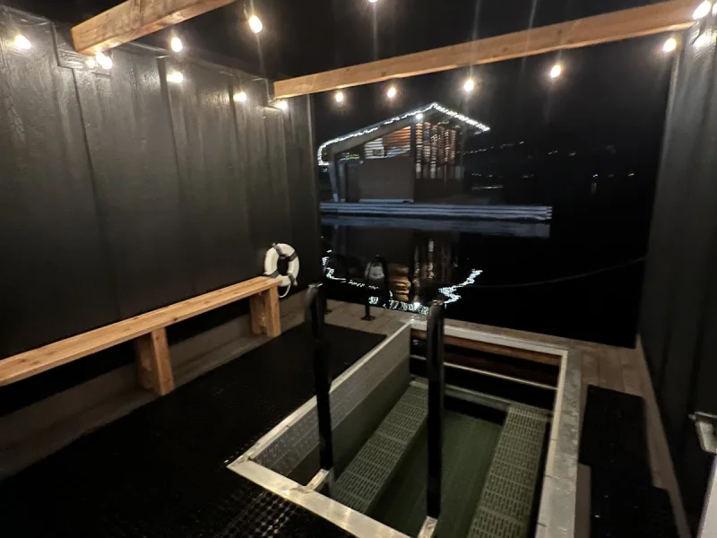 Floating sauna deck with plunge pool, benches, and marina night views