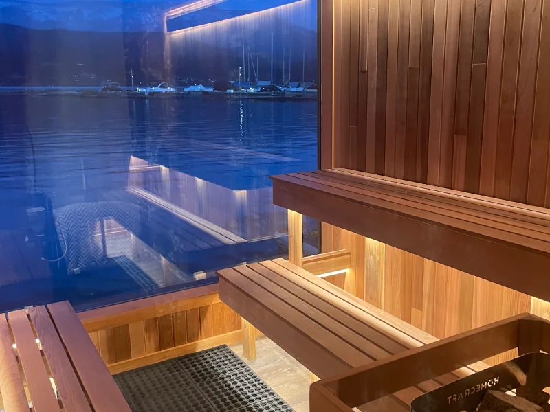 Cozy cedar sauna interior with panoramic lake views at dusk
