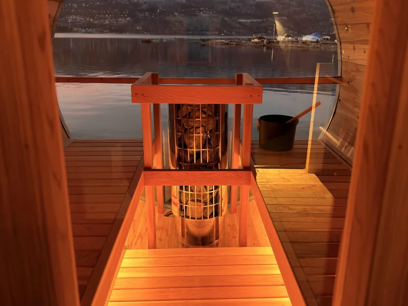 Wood-fired barrel sauna with lake and mountain views at sunset
