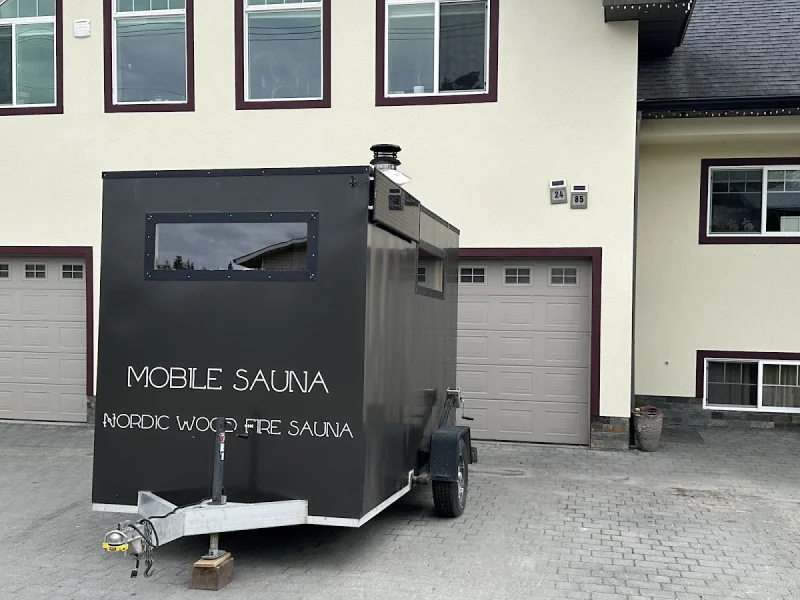 Black mobile sauna trailer parked in a residential driveway with house backdrop