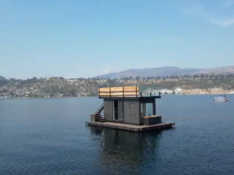 Small floating sauna retreat centered on a serene lake with distant hills